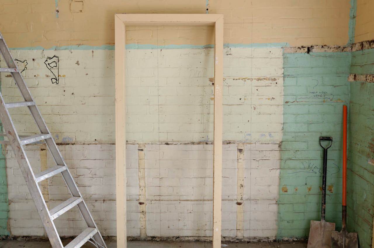 Renovation scene featuring ladder, frame, and tools against partially demolished walls.